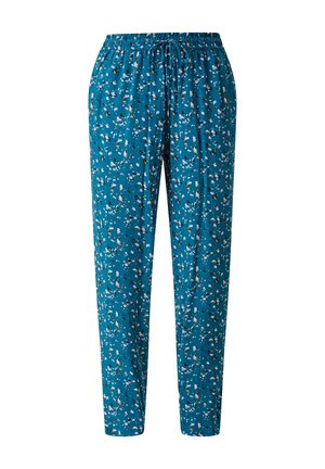 Woman wearing teal drawstring pants with small floral print paired with black woven slip-on sandals and a white top.