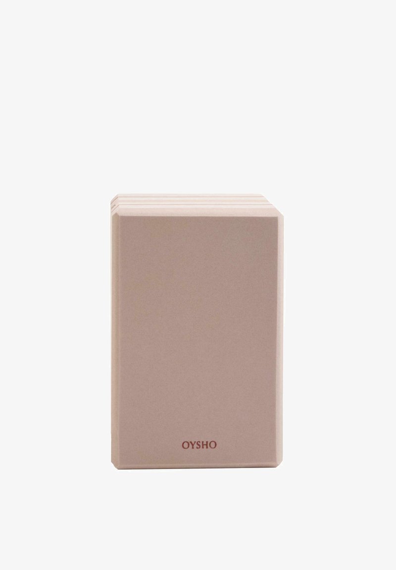 Stack of beige rectangular yoga blocks with smooth surfaces and "OYSHO" printed in small red letters on one block.
