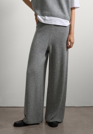 Pantalones de pierna ancha de punto gris con una textura suave, cinturilla acanalada y costuras sutiles, combinados con zapatos planos negros.