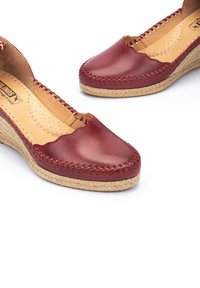Espadrilles en cuir rouge avec un bord festonné, semelle intermédiaire en jute tissé et couture décorative sur le dessus.