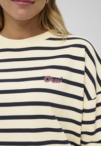 Gestreiftes Sweatshirt in Gelb und Marineblau. Verfügt über einen Rundhalsausschnitt und ein pinkes, aufgesticktes "Oui"-Logo auf der Brust. Weiches Baumwollmaterial.