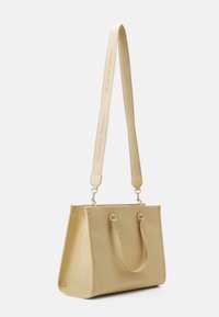 Sac fourre-tout en simili cuir jaune, de forme structurée, avec deux poignées supérieures, une bandoulière amovible et des accents en métal doré.