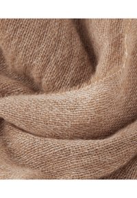 Miękka beżowa tkanina o plecionej, luźno utkanej strukturze, delikatnie złożona, aby pokazać szczegóły włókien i naturalne ciepło.