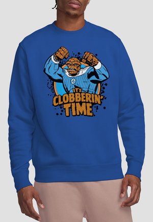 Blaues Sweatshirt mit einem Grafik eines Charakters mit geballten Fäusten, der ein blau-weißes Outfit trägt, mit dem Text "Es ist Zeit zum Klopfen."