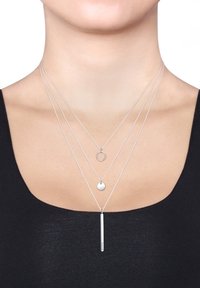 Sølvlagde halskæder med en cirkulær vedhæng, en lille skive og et lodret stangvedhæng, alle på fine, delikate kæder.
