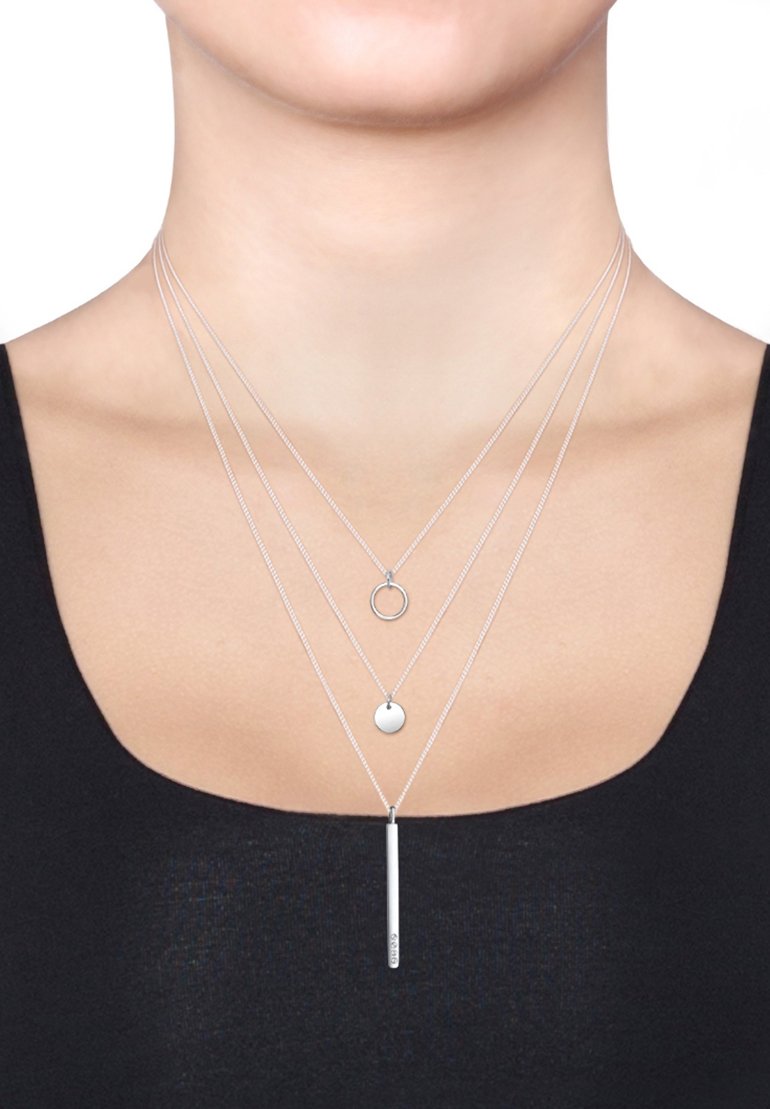 Sølvlagde halskæder med en cirkulær vedhæng, en lille skive og et lodret stangvedhæng, alle på fine, delikate kæder.