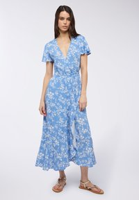 Abito avvolgente blu a fiori con maniche corte e scollatura a V profonda. Presenta una vita con laccetto e una gonna morbida, realizzato in tessuto leggero. Sandali inclusi.