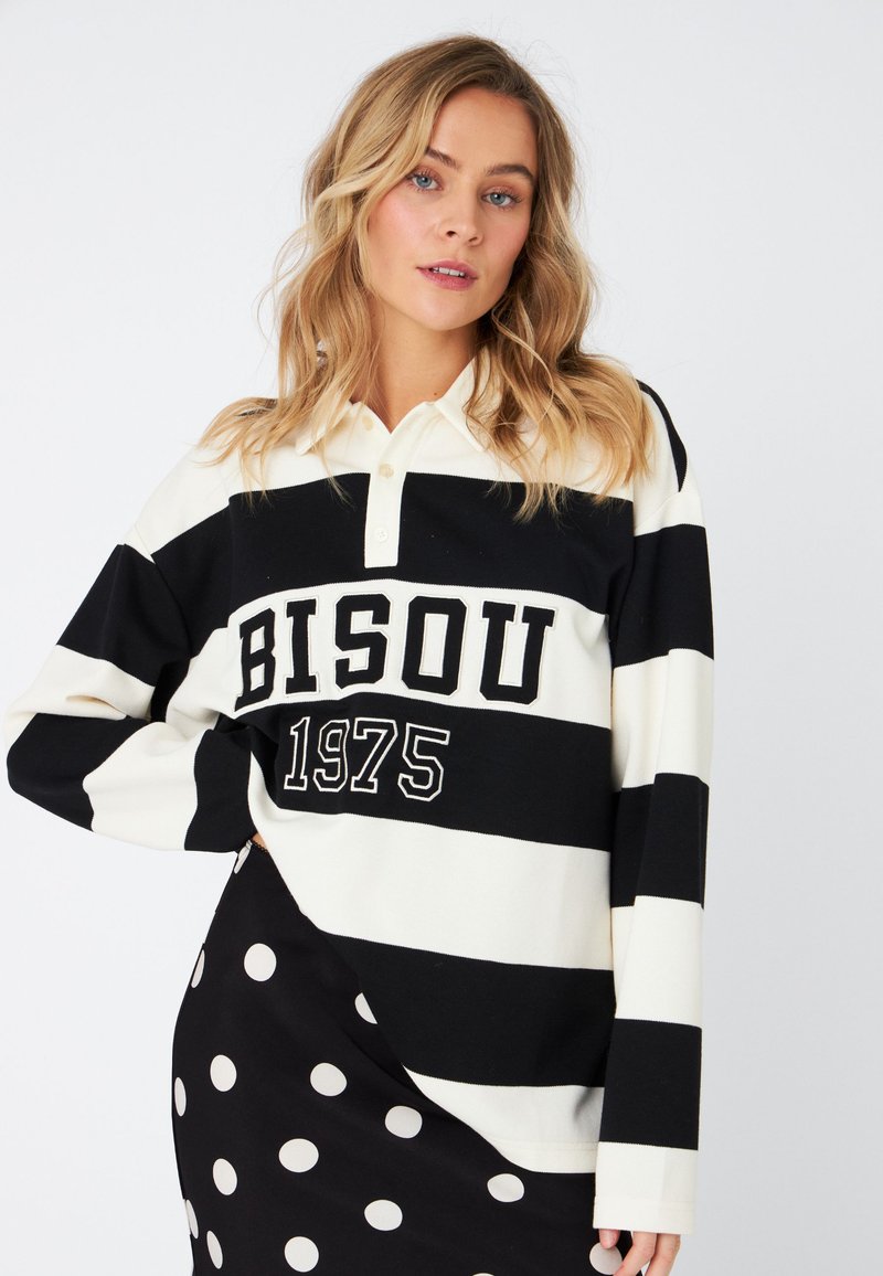 Long-sleeve polo shirt with black and white horizontal stripes. Features a collar, button closure, and "BISOU 1975" print. Soft fabric.