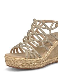 Sandalo wedge beige con design a strisce incrociate adornato da strass, posizionato su una piattaforma in juta intrecciata con una finitura testurizzata.