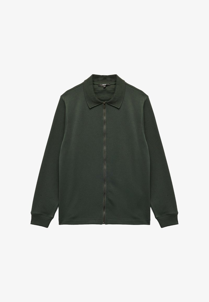 Tumma vihreä vetoketjullinen takki, jossa on ribatty kaulus, pitkät hihat ja pehmeä, sileä pinta. Ominaisuuksina on istuva vyötärö ja ei ylimääräisiä kuvioita.