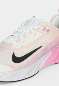 Άσπρο και ροζ παπούτσι για τρέξιμο Nike με μαύρο λογότυπο swoosh και λευκά κορδόνια σε λευκό φόντο.