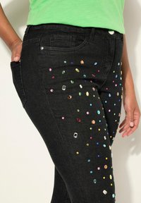 Zwarte denim jeans met kleurrijke edelsteenversieringen verspreid over de voorkant, met een slim fit en een vijf-pocket ontwerp.