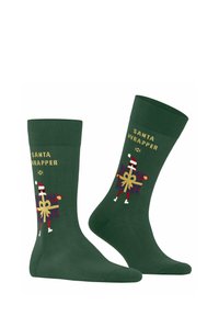Grüne Socken mit dem Text "SANTA WRAPPER" in Gelb. Das Design zeigt eine festliche Figur, die ein Geschenk mit roten und goldenen Akzenten hält.