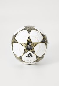 Balle de soccer blanche avec des accents noirs et dorés, présentant un design d'étoile, le logo de la Ligue des champions de l'UEFA et le logo Adidas. Texture lisse.