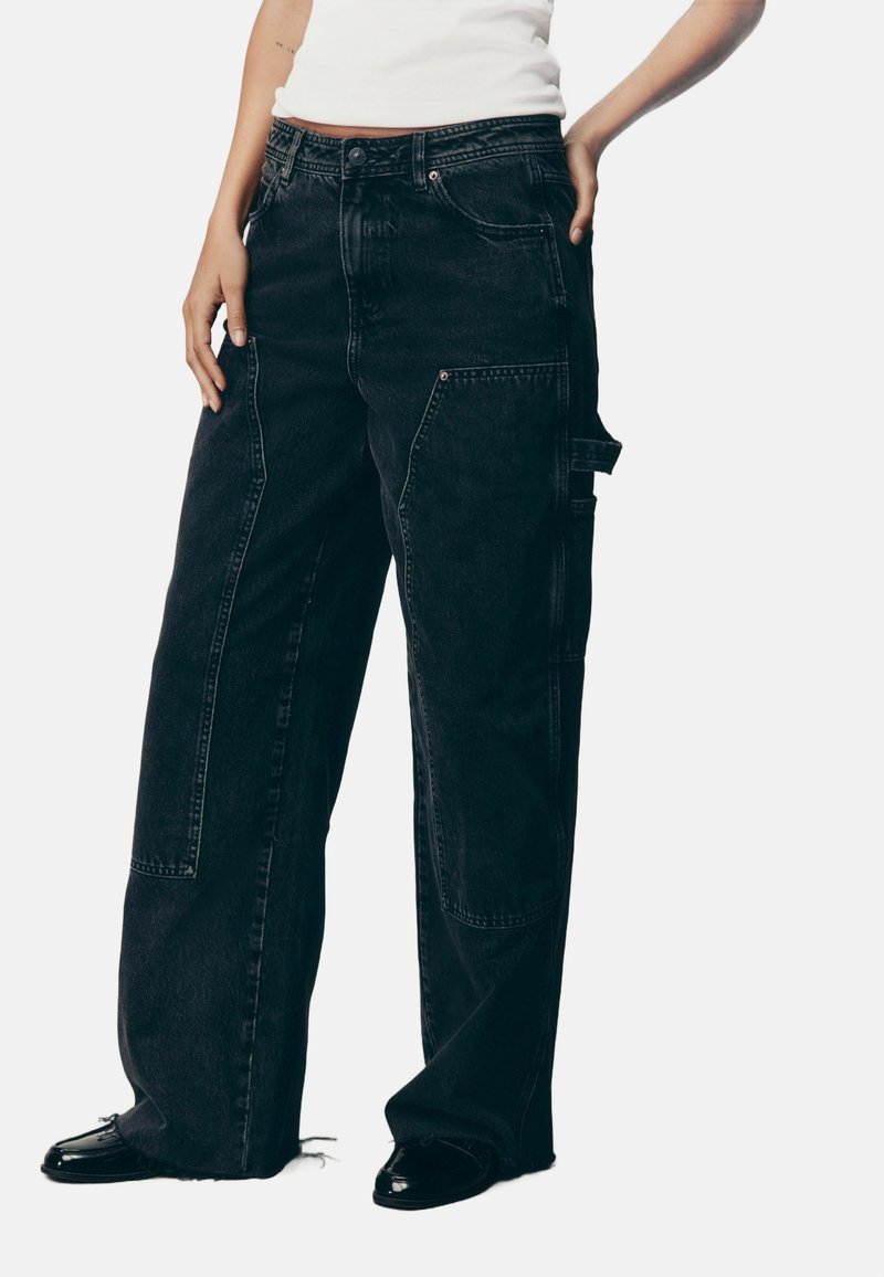 Jeans cargo cu croi larg, din denim negru, având multiple buzunare, închidere cu buton și detalii cu tiv desfăcut. Textură netedă, realizate dintr-un material rezistent.