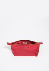Bolsa de cosméticos roja con un acabado brillante, cremallera dorada y logotipo grabado. El interior presenta un forro suave. Pequeña correa lateral para un manejo fácil.