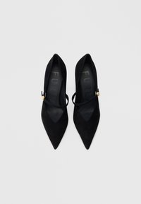 Μαύρα σουέντ γοβάκια με μυτερή μύτη, μία λουρίδα και χρυσές λεπτομέρειες. Λιτή εσωτερική επένδυση και ανθεκτικές σόλες για σταθερότητα.