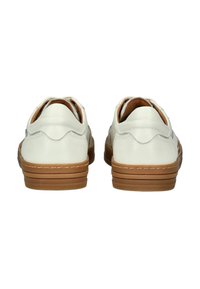 Scarpe in pelle bianca con un design smerlato sul tallone e suole in gomma marrone. Texture liscia con dettagli di cucitura sui lati.