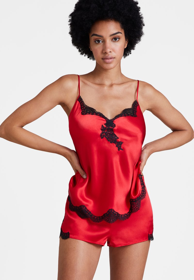 Ensemble de nuit en satin rouge avec de délicates finitions en dentelle noire sur le haut et le short, doté de bretelles ajustables fines et d'une texture douce.