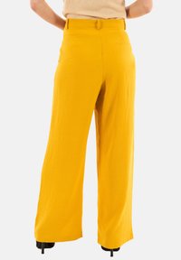 Pantaloni a gamba larga di un brillante giallo, realizzati in un tessuto texture, con vita alta e un design minimale completo di tasche posteriori.