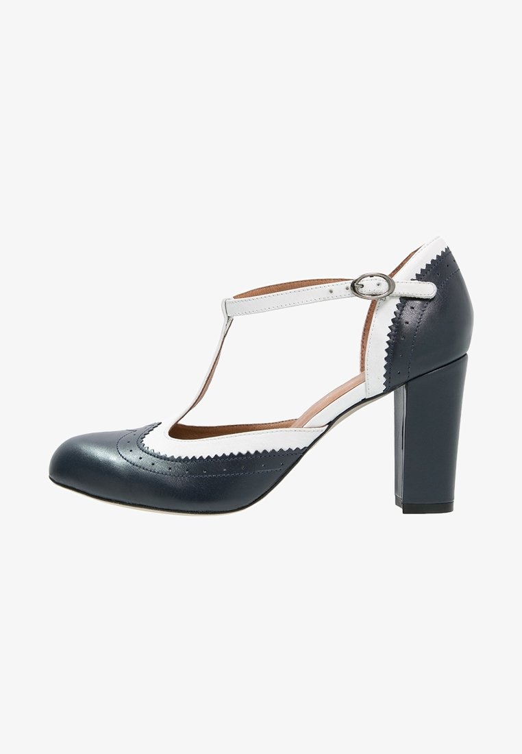 Chaussure à talon haut noire et blanche avec brides en T, fermeture à boucle, bout rond et finition festonnée.