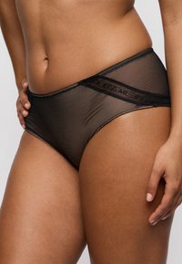 Ropa interior hipster negra de malla con una textura translúcida, con una banda elástica decorativa que lleva el texto "KISS ME" en un lado.