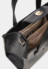 Borsa a mano in pelle sintetica nera con doppio manico, hardware color oro e interno beige che presenta più scomparti e un motivo con logo.