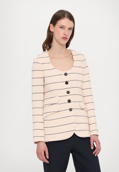 Stripet blazer i lys creme med mørke vandrette striber, der har en scoop neckline, fem knaplukninger og to frontlommer.