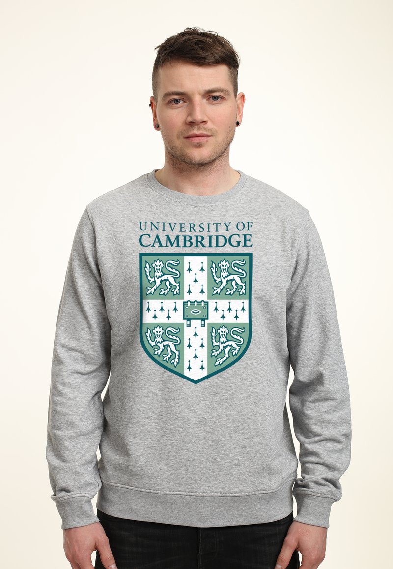 Felpa grigia con il blasone dell'Università di Cambridge. Il design include elementi color turchese e bianco con motivi di leone e freccia.