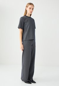 Marineblauwe set bestaande uit een T-shirt met korte mouwen en wijde broek, met een geometrisch ruitpatroon en een relaxed fit.