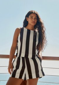 Set di top a canotta e pantaloni corti a righe bianche e nere, con un design a taglio dritto e tessuto leggero, dalla consistenza morbida.
