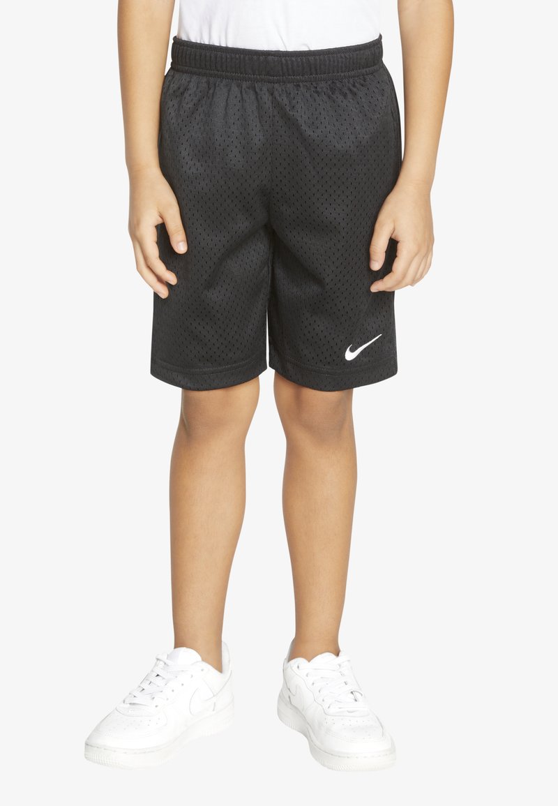 Sorte mesh idrettsshorts med elastisk midje, med en hvit Nike-logo på venstre ben. Brukt med hvite joggesko.