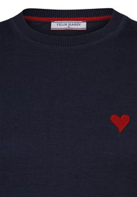 Marineblauer Pullover mit ribbeliger Textur, mit einem roten gestickten Herzen am unteren linken Rand. Das Etikett trägt die Aufschrift "FELIX HARDY", Größe S.