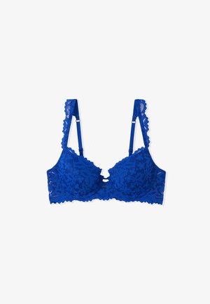 Reggiseno blu in pizzo con un motivo floreale, coppe imbottite, spalline regolabili e bordi ondulati. Presenta un dettaglio decorativo al centro.
