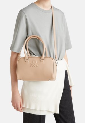 Jasnoróżowa skórzana torebka z dwoma górnymi uchwytami i odpinanym paskiem na ramię. Posiada subtelne tłoczenie logo oraz srebrne akcenty metalowe.