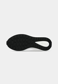 Semelle de chaussure noire et blanche avec un motif rectangulaire et le nom de la marque visible au niveau du talon, sur un fond clair uni.