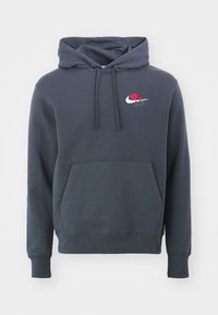 Hoodie i mörkgrå bomullsblandning. Har en känguruficka, ribbade ärmar och broderad ros med Nike-logotyp.