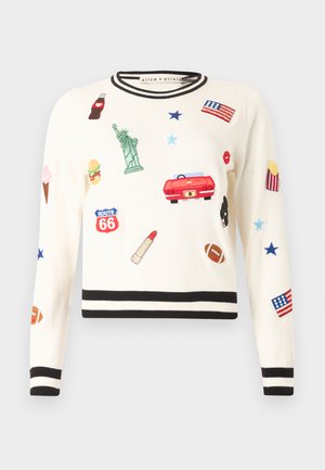 Λευκό πουλόβερ με μαύρες ρίγες στα μανίκια και στο τελείωμα, διακοσμημένο με μπαλώματα με θέμα την Αμερική, όπως το Άγαλμα της Ελευθερίας, πινακίδα της Route 66 και κόκκινο αυτοκίνητο.