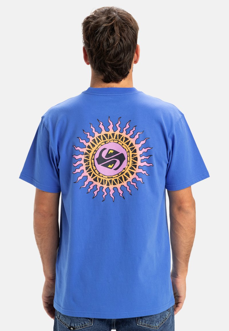 Blaues Baumwoll-T-Shirt mit einem runden, mehrfarbigen Sonnengrafik auf dem Rücken, die sich windende Strahlen und ein zentrales Logodesign zeigt.