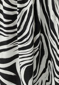 Svartvitt tyg med zebrarandmönster, med djärva, svepande linjer och en strukturerad väv.