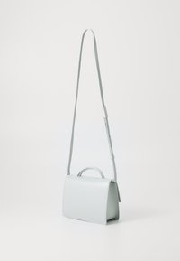 Sac à main en cuir bleu clair avec une forme structurée, une poignée supérieure et une bandoulière réglable. Texture lisse avec des détails de couture minimaux.