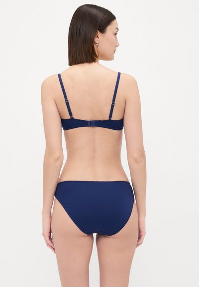 Navy blue bra and matching brief set, made of smooth fabric, featuring adjustable straps and delicate scalloped edges on the waistband.