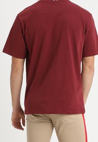 Maroon cotton t-shirt with short sleeves, a crew neck, and a relaxed fit. Seamless back and lightweight texture. No visible logos or patterns.