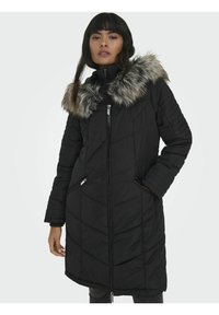 Manteau d'hiver matelassé noir avec un col en fausse fourrure, fermeture éclair sur le devant et poches latérales. Présente une longueur longue et des poignets côtelés.