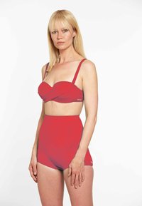 Sarkans bikini komplekts, kas ietver savīti bandeau augšdaļu, regulējamus siksniņas un augsto jostasvieta apakšdaļu, izgatavots no gludas elastīgas auduma.