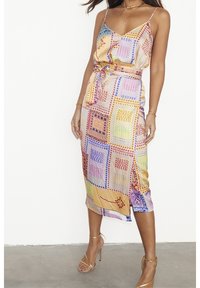 Bunt bedrucktes Kleid in Midi-Länge, mit verstellbaren dünnen Trägern, tailliertem Bund und geometrischen Mustern in den Farben Pink, Blau und Gelb.