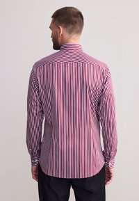 Langärmeliges Hemd mit vertikalen roten und weißen Streifen, aus gewebtem Stoff, mit spitzem Kragen und geknöpften Manschetten.