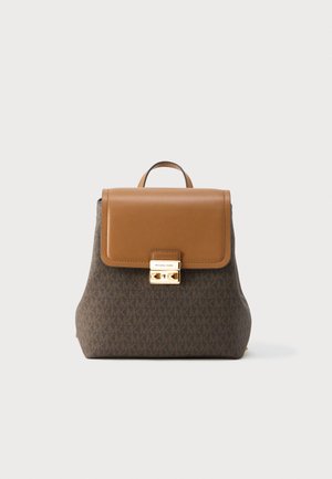 Rudos medžiagos kuprinė su šviesios odos atvartėliu, auksinės spalvos metalinėmis detalėmis ir logotipo akcentais. Turi viršutinę rankeną ir modernią, struktūruotą formą.