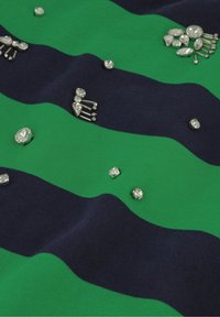 Gestreepte stof in groen en marineblauw, versierd met verschillende heldere rhinestones. Soepele textuur met een zachte val.