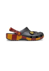 Zueco de plástico negro con una correa trasera elevada, acentos rojos y una suela de rayas multicolores en amarillo y rojo. Presenta pines decorativos en la parte superior.